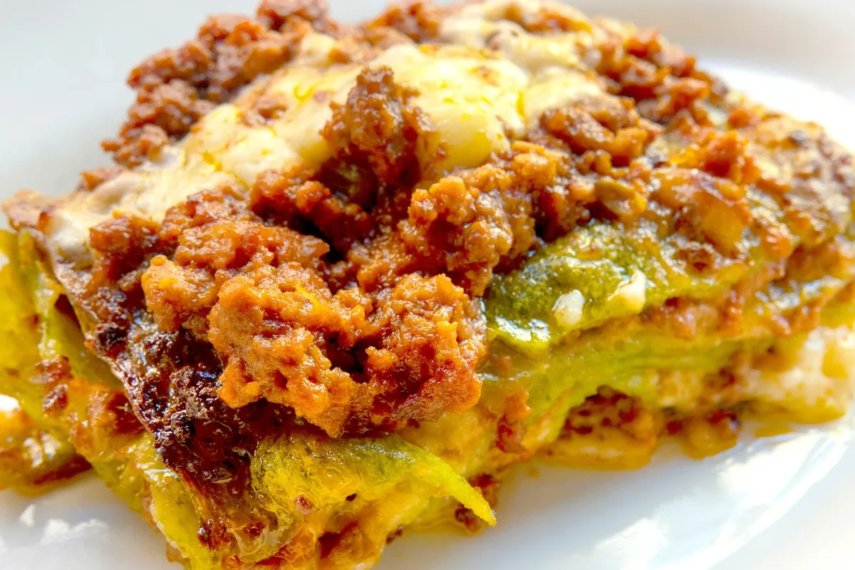 Porzione di lasagne alla zucca e salsiccia con la sfoglia verde, appena gratinate