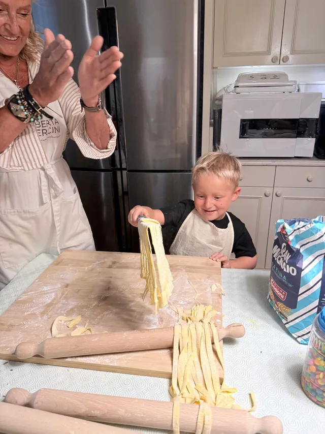 Un bambino stende le tagliatelle durante la lezione